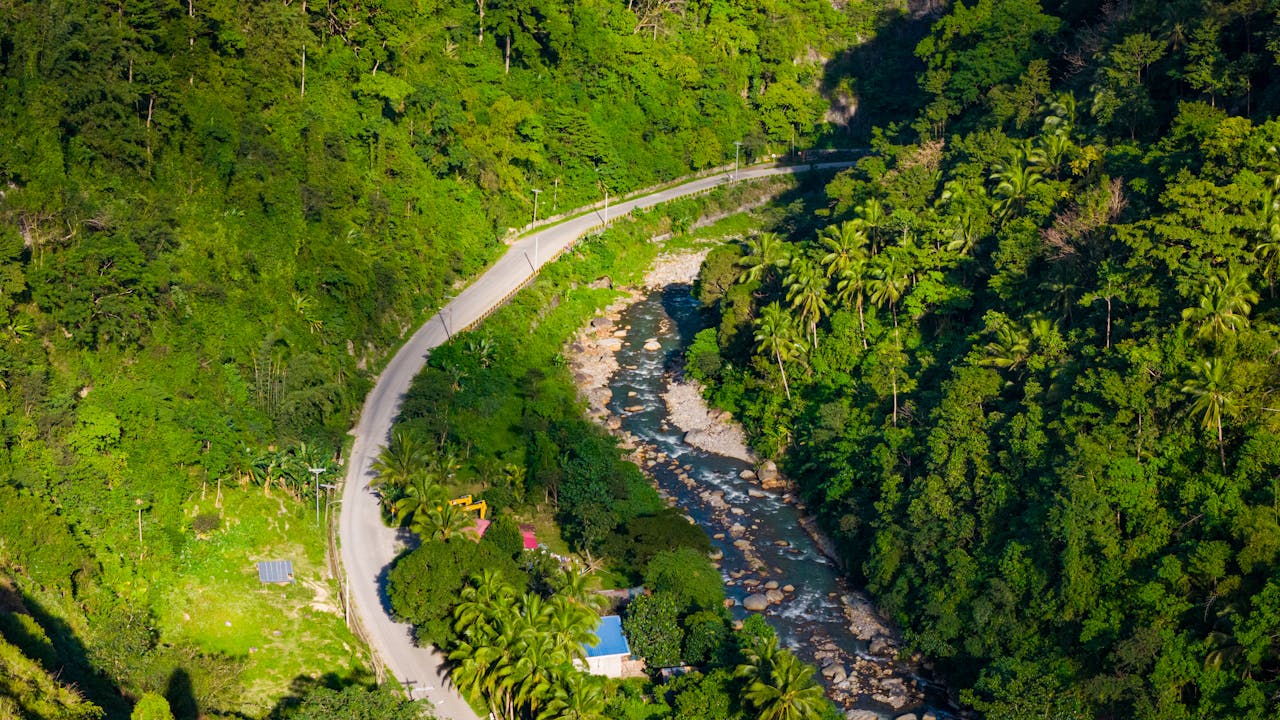 A breathtaking aerial view of a river winding through lush tropical rainforest in Cebu City, Philippines.