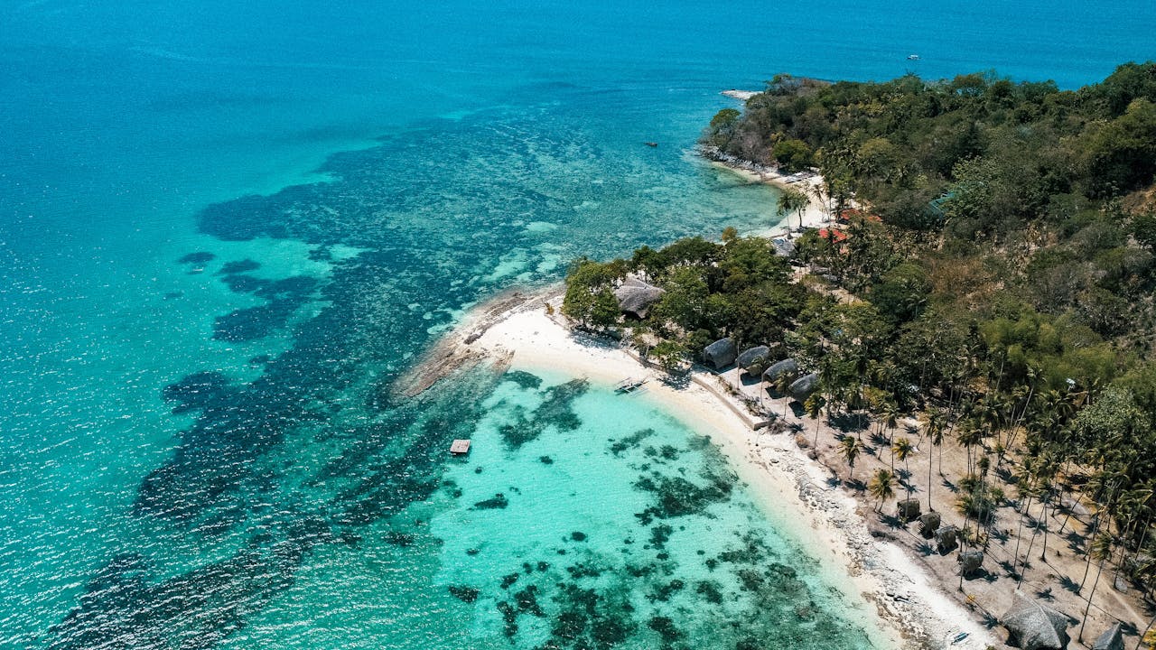 Stunning aerial shot of a pristine tropical beach with turquoise waters and lush greenery.