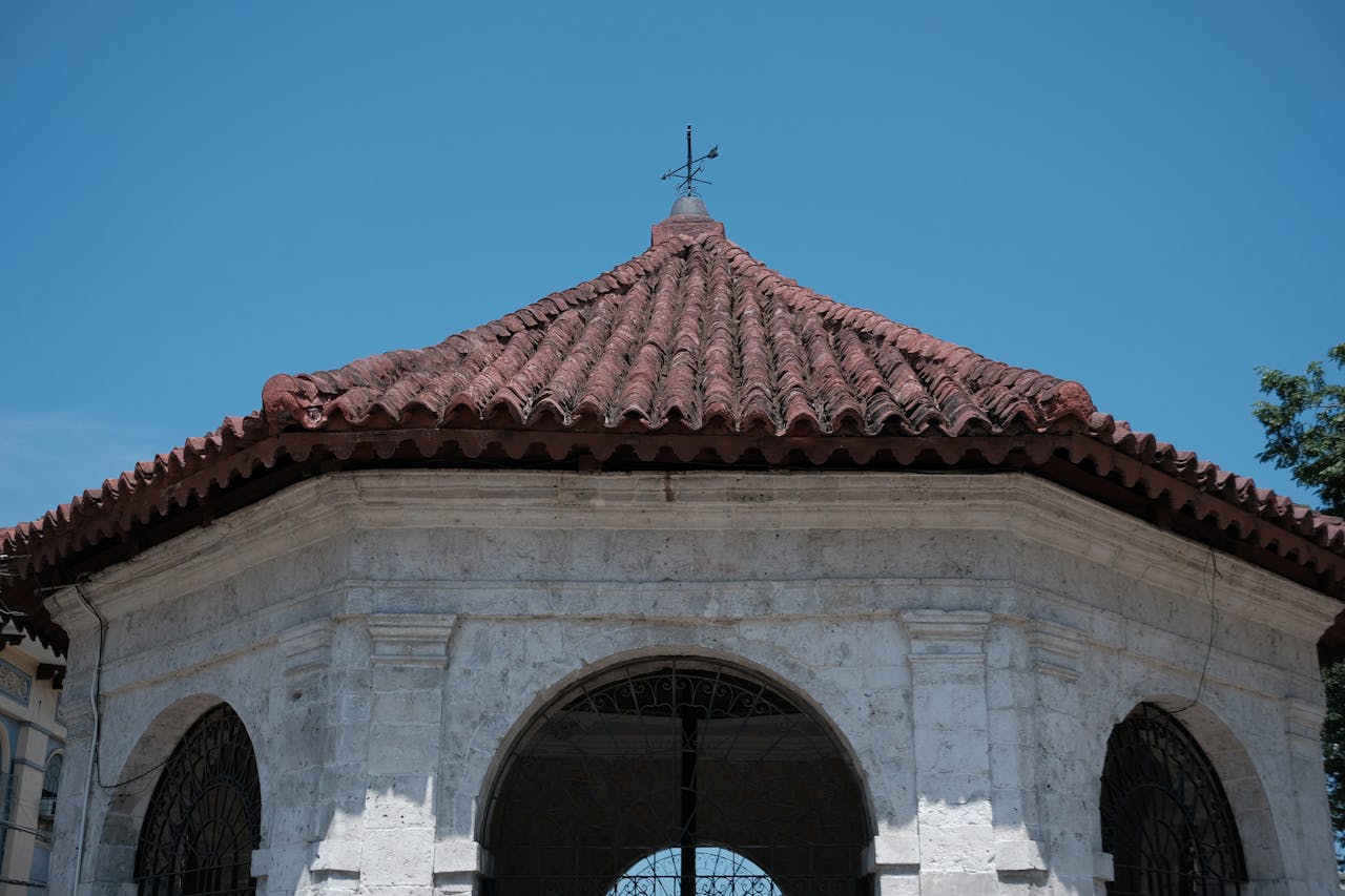 A historical view of Magellan's Cross Pavilion in Cebu City, Philippines, with a clear blue sky.