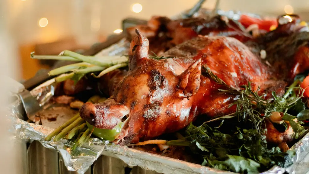 A whole golden brown Cebu lechon roasted pig stuffed with lemongrass and herbs on a serving tray