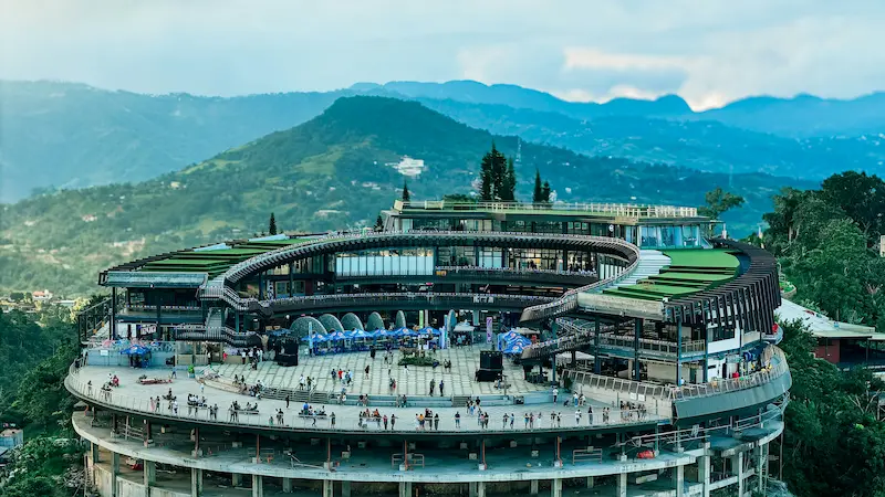 The modern multi-tiered circular viewing deck architecture of TOPS Cebu located high in the Busay hills with mountains in the background