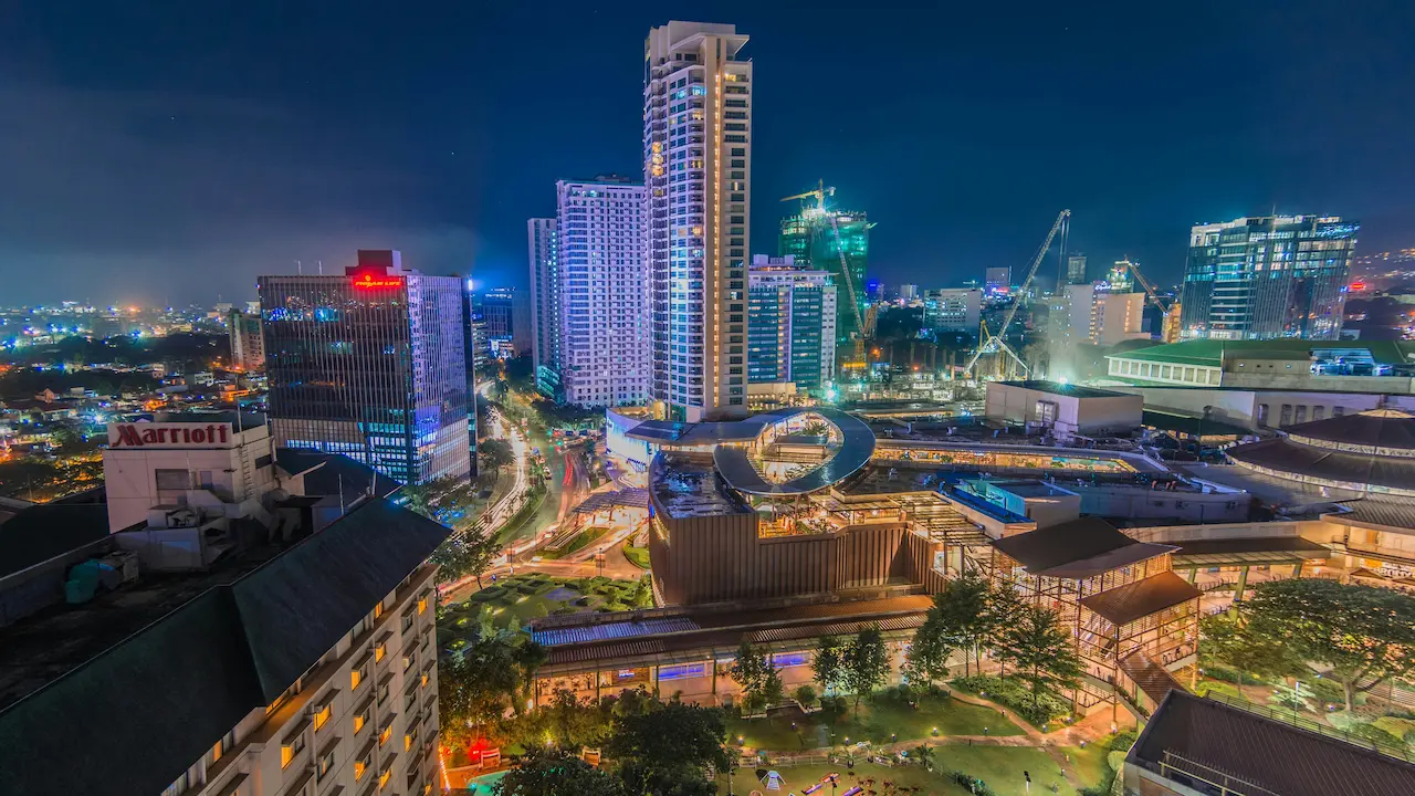 Night skyline of Cebu Business Park with high-rise buildings, bright city lights, traffic trails, and commercial areas near Ayala Center Cebu.