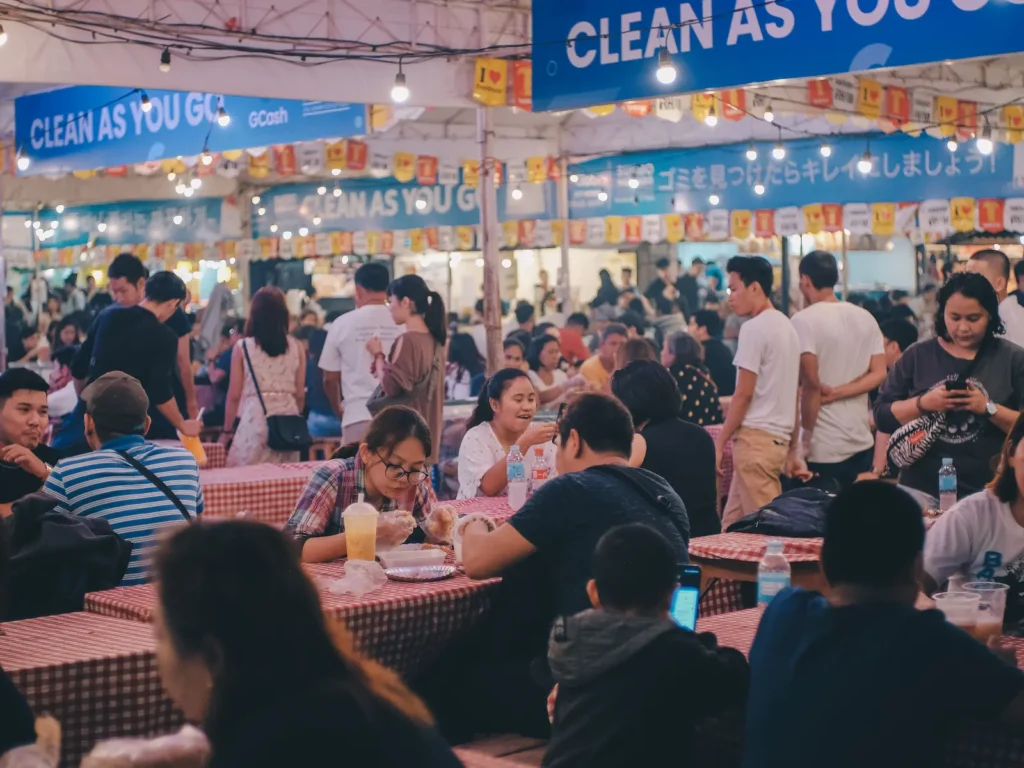 Crowded dining area at Sugbo Mercado in Cebu IT Park with diners, food stalls, and warm night market lights.